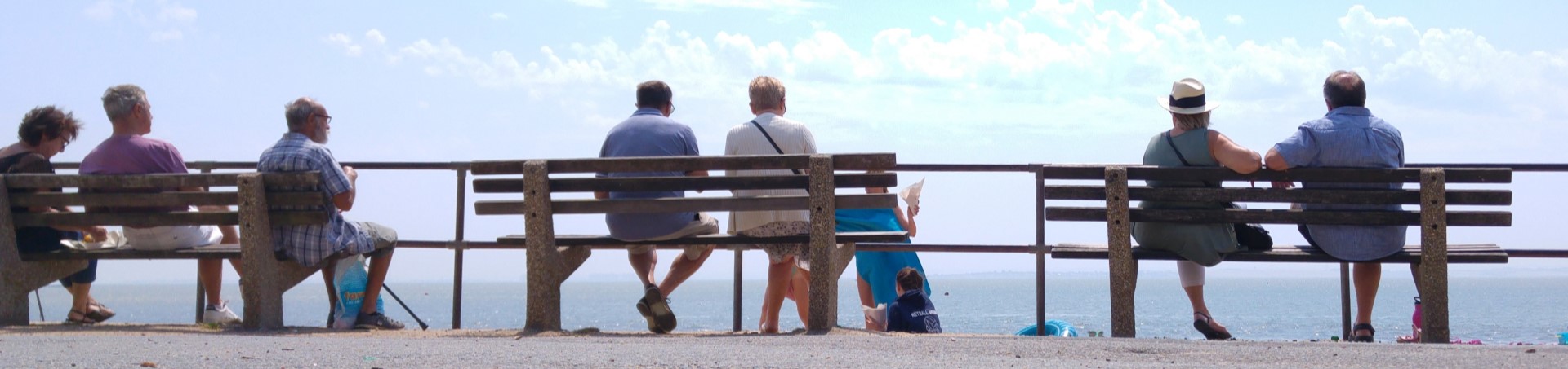 People sitting on benches overlooking the sea in Old Leigh.