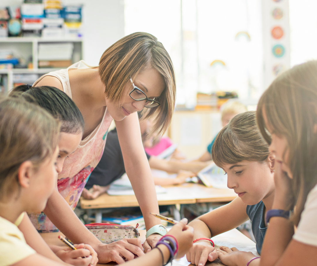 Teacher with 4 children sitting at a table working together.