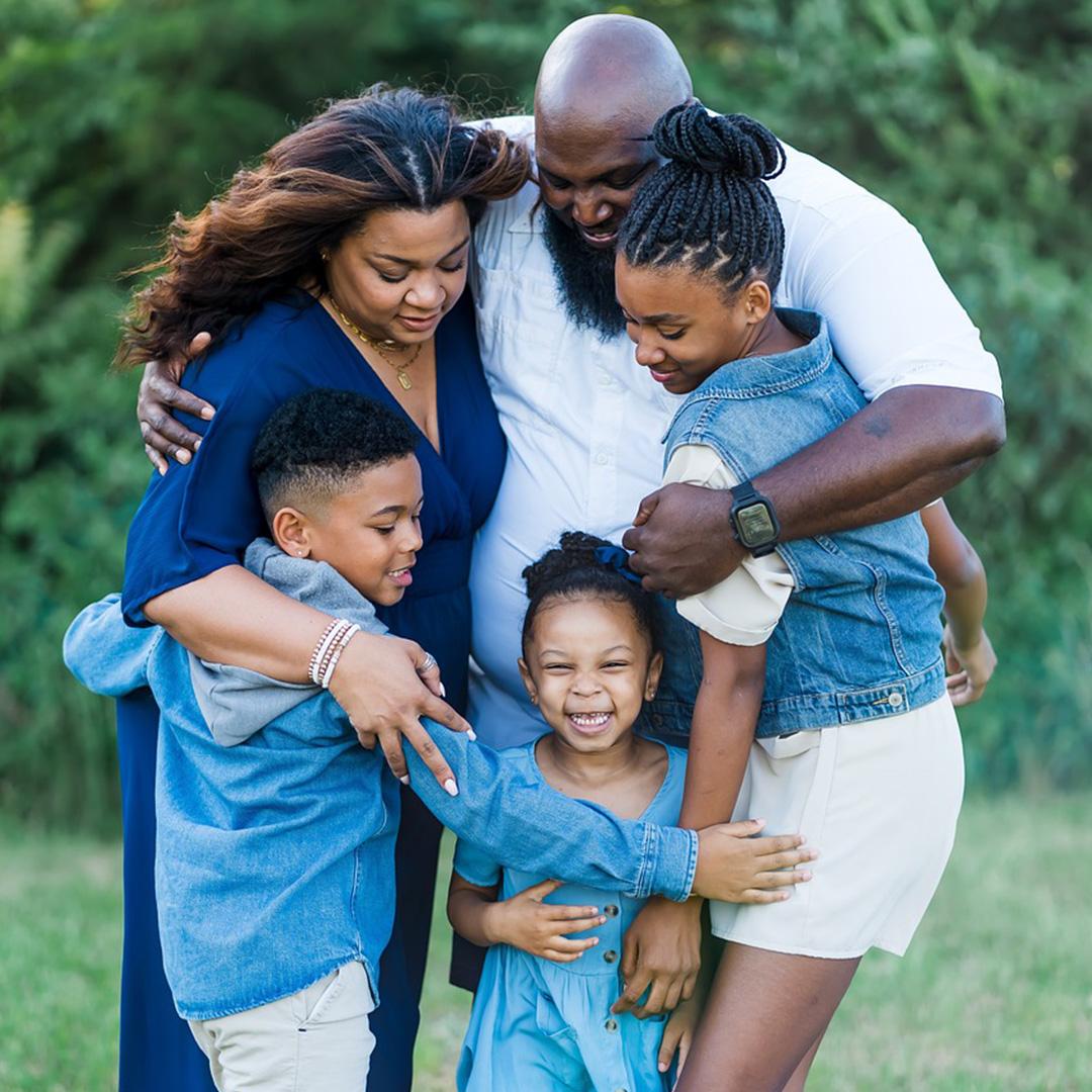 A family, two parents, two girls and a boy, hugging