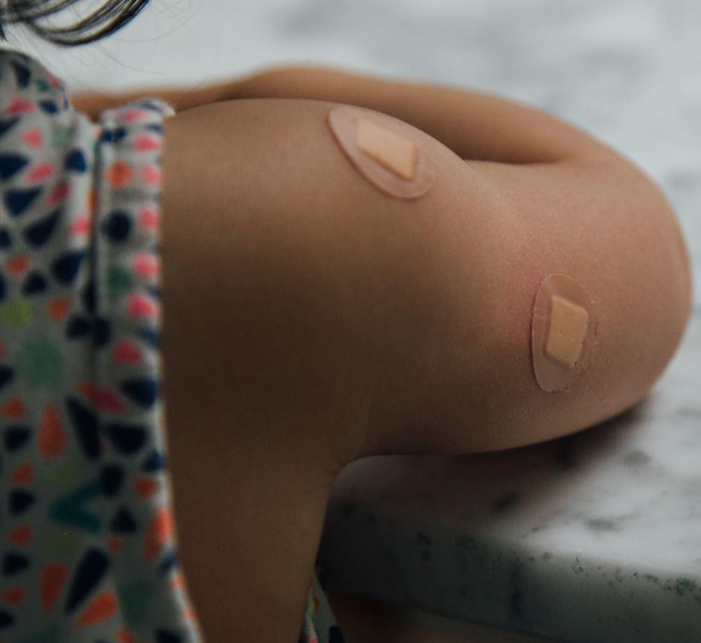 a young girl&#039;s arm after receiving a vaccination, with two small plasters on the arm