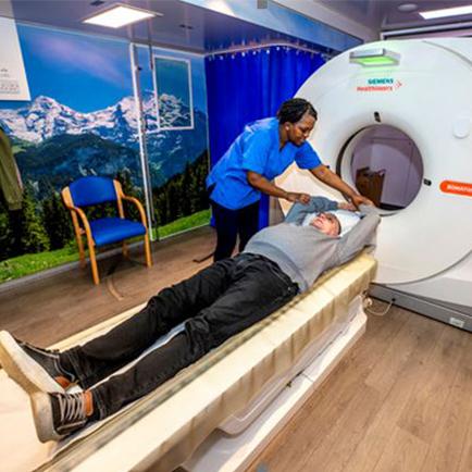 A man using a lung cancer scanning detaction machine being assisted by a nurse