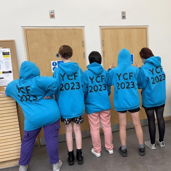 Five children all wearing blue jumpers with the text YCF 2023 on the back