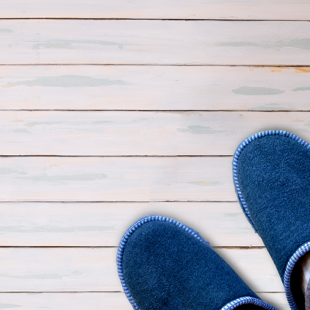 A pair of blue slipper shoes in the bottom right hand corner, on pale ash coloured floor boards