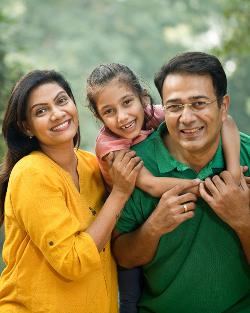 photograph of a family - a male adult, a female adult and a child. all 3 are smiling and cuddling together