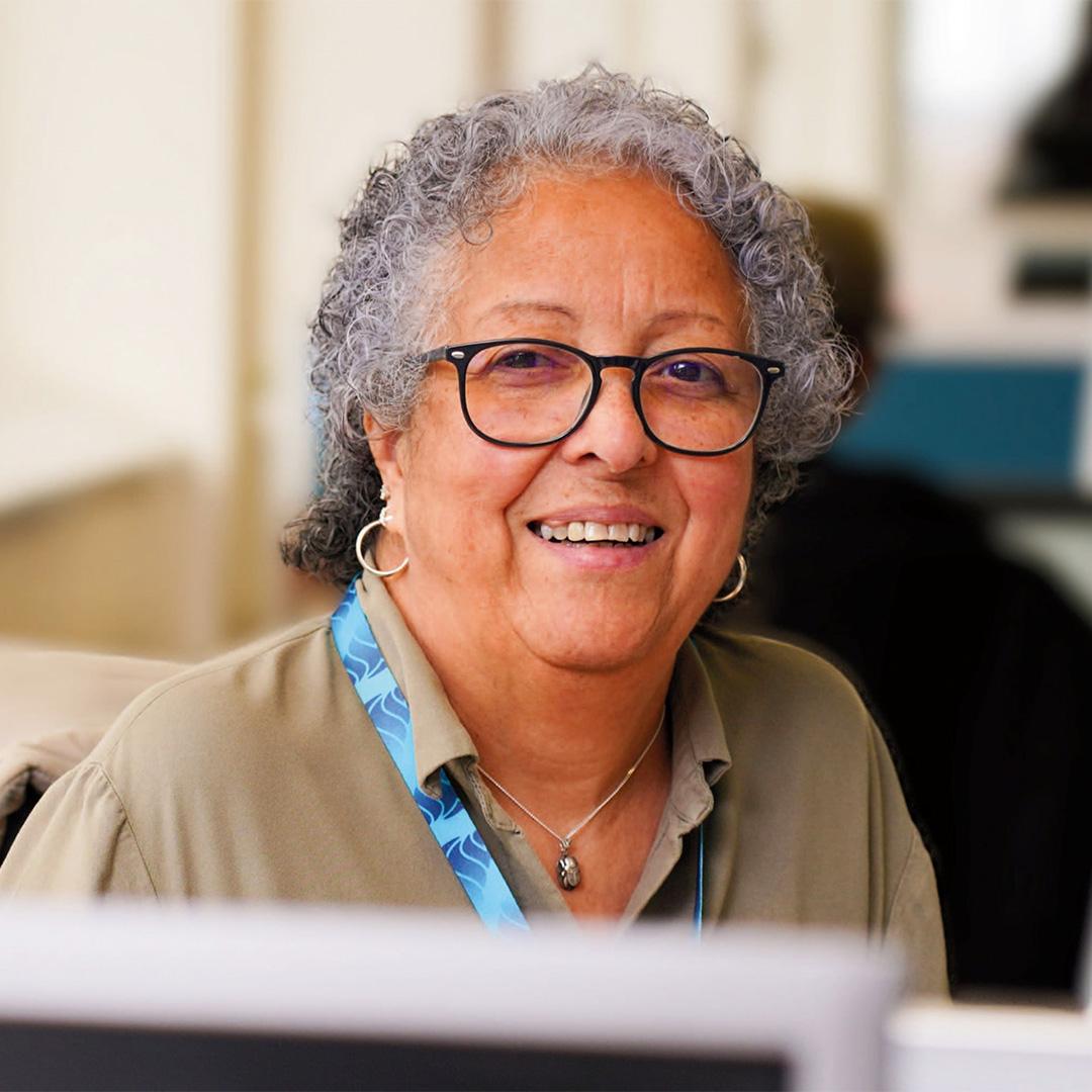 An elderly woman looks at the camera and smiles