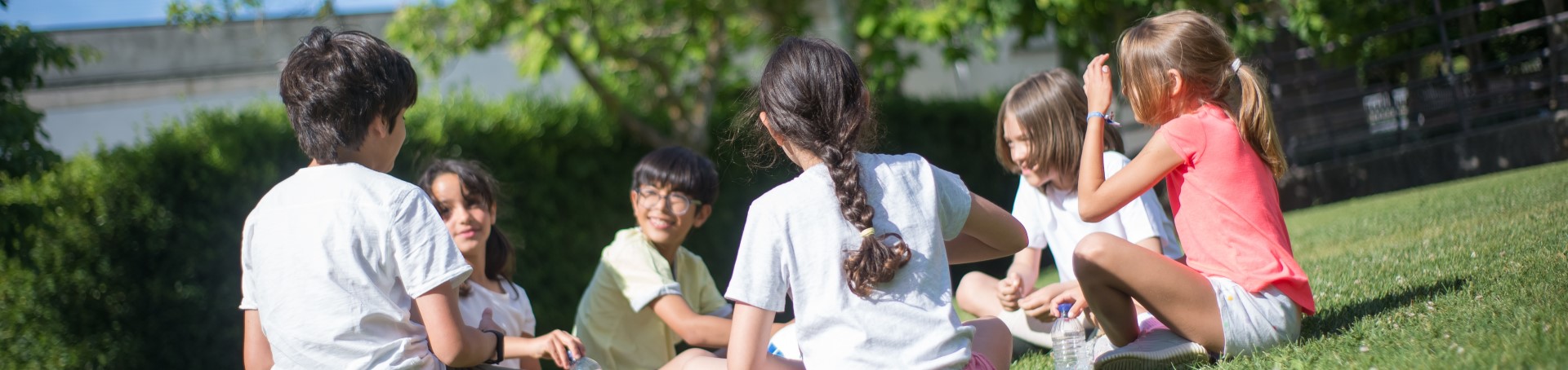 Children sitting in a circle on some grass.