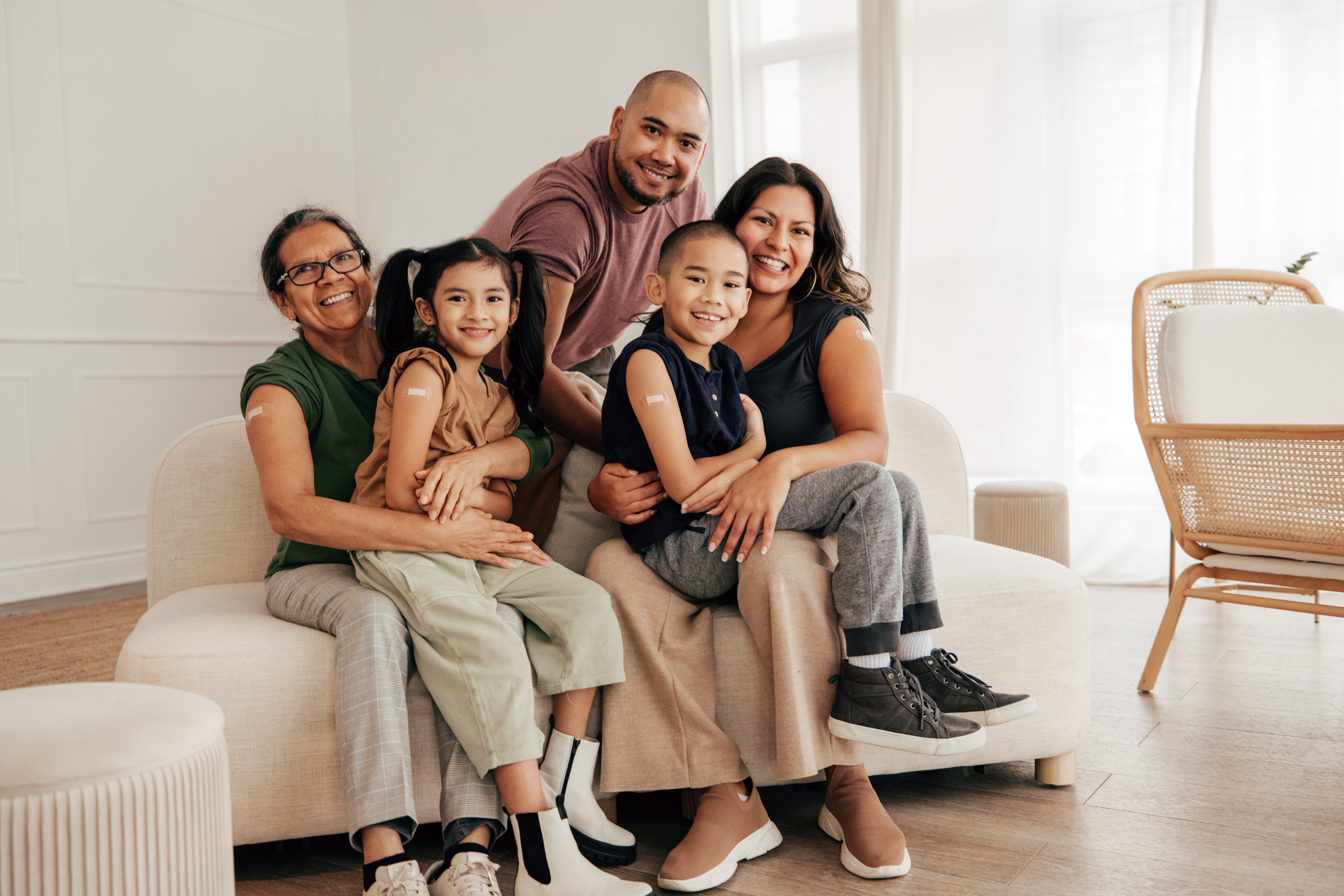 Family sat together on the sofa with plasters on their upper arms