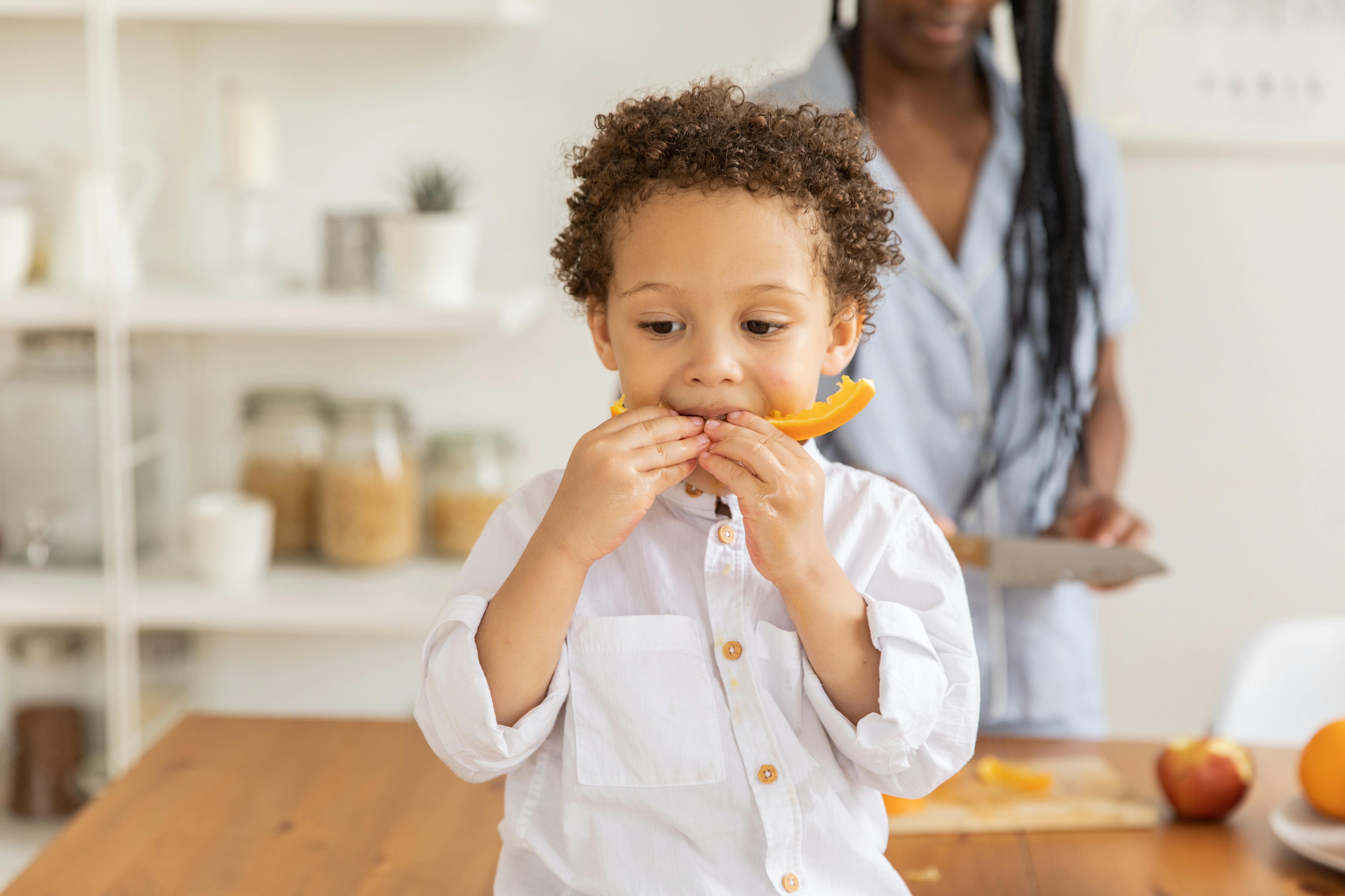 young child eating an orange