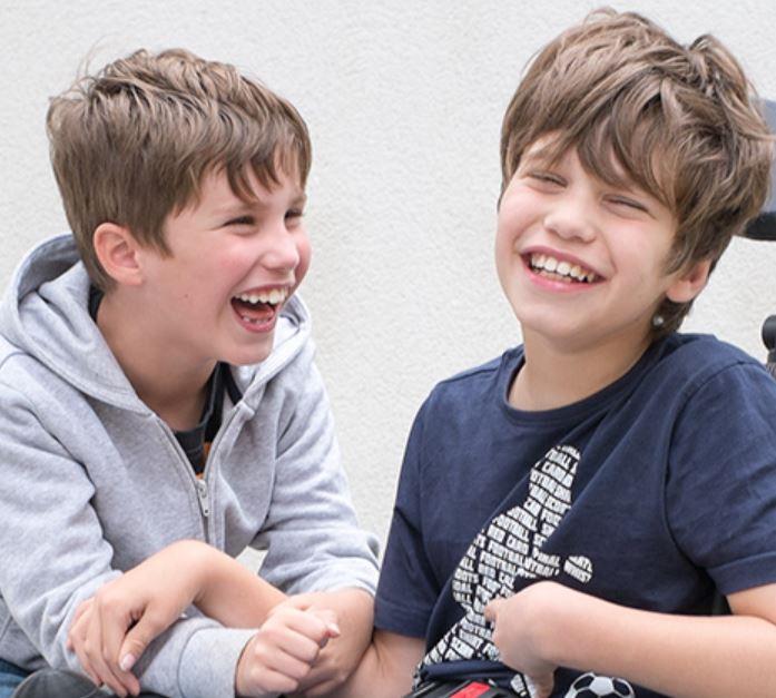 Two brothers laughing together. One of the boys is in a wheelchair
