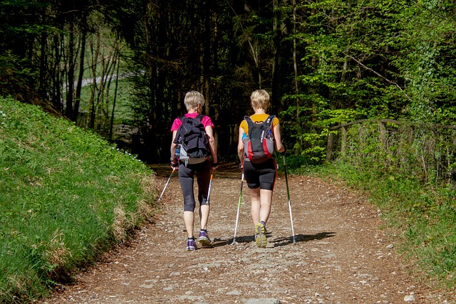 Two women wlaking with walking poles in the woods.