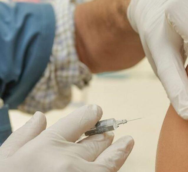 Closeup of a vaccination needle about to enter a teen&#039;s arm